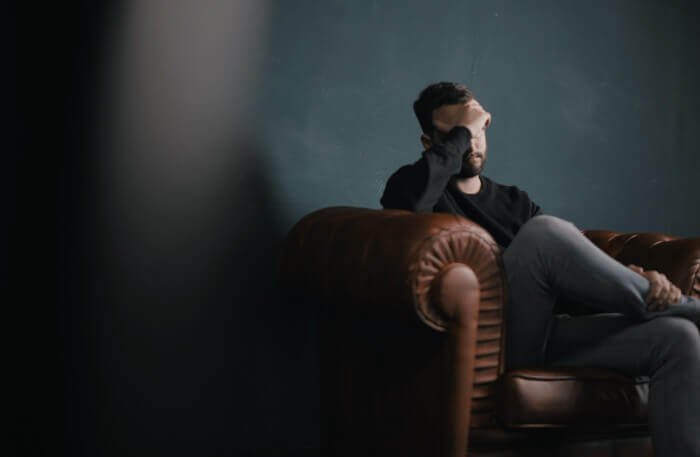 Depressed man sits with head in hands in therapy session - cognitive hypnotherapy for depression