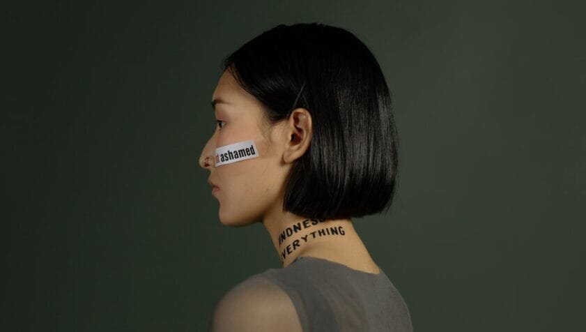 Trauma Therapy London, woman wearing words like shame on her face and neck
